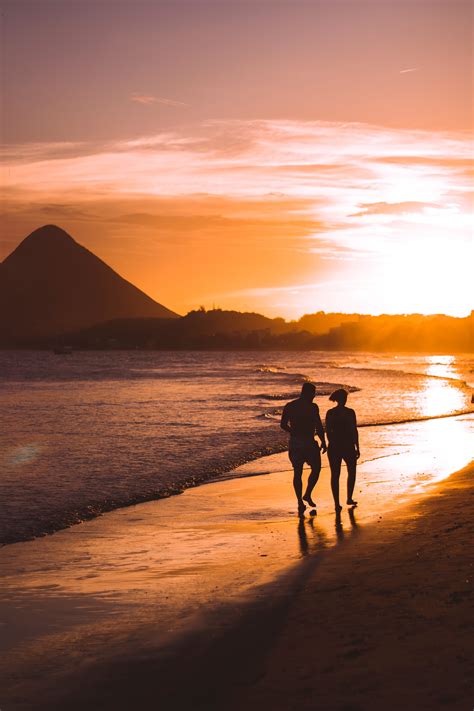 Silhouette of Two People Walking on Beach during Sunset · Free Stock Photo