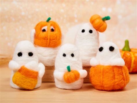 there are several small stuffed animals made to look like ghostes with pumpkins in the background