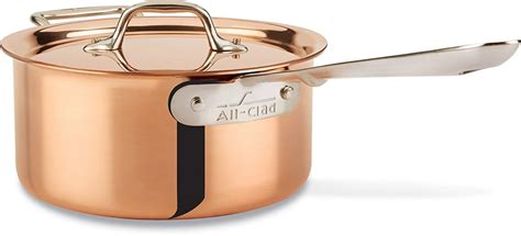 an all - clad copper sauce pot with a lid and spoon in the bottom, on a white background