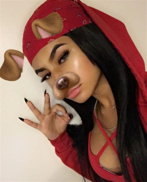 a woman with long black hair wearing a red hoodie and holding a fake nose