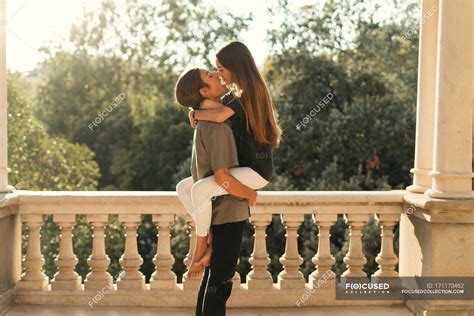 Side view of boyfriend holding girlfriend on hands over ornate marble ...