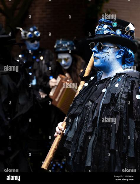 Morris Dancers with full makeup and painted faces and playing an accordion. Traditional dark ...