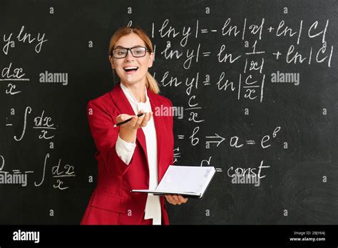 Beautiful math teacher with book near blackboard in classroom Stock Photo - Alamy