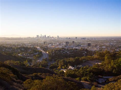 a view of the city from atop a hill with trees and hills in the foreground