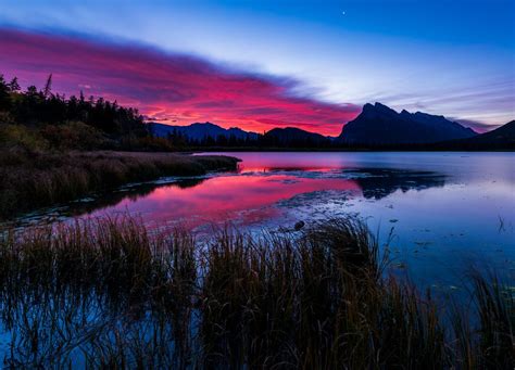 a beautiful sunset over a lake with mountains in the background