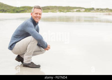 Man crouched down at the shore Stock Photo - Alamy