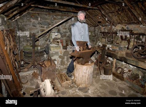 Blacksmith in old Smithy with tools in traditional crofters barn Museum of Island life Isle of ...