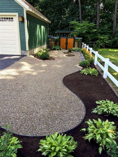 a gravel driveway next to a white fence