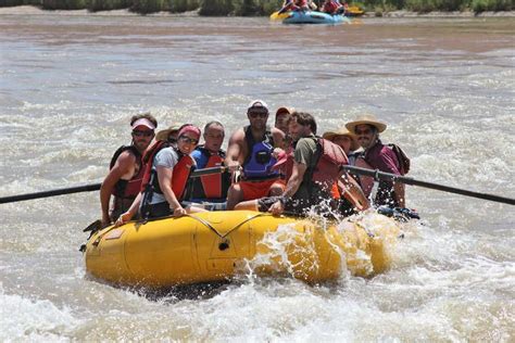 a group of people riding on the back of a raft down a river