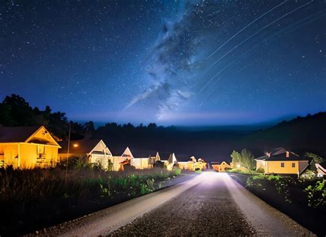 Premium AI Image | village on night starry sky glowing road landscape on shutter speed