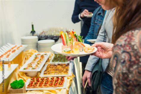 Catering buffet table with food and snacks for guests of the event. Group of people in all you ...