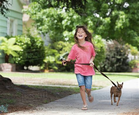 Girl walking dog in street - Stock Photo - Dissolve