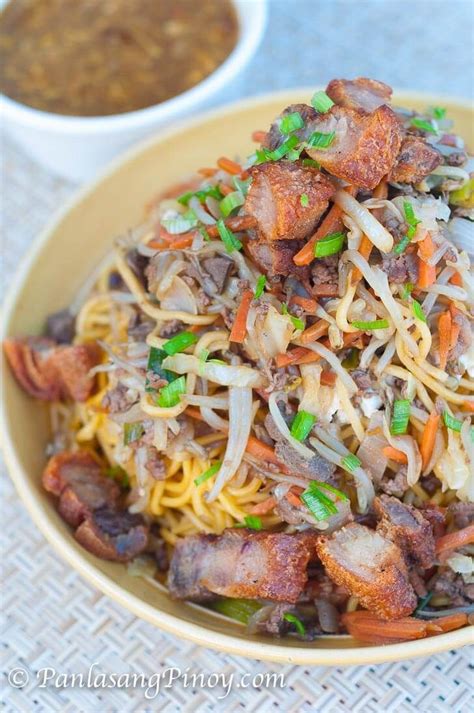 a bowl filled with noodles and meat on top of a table next to some ...