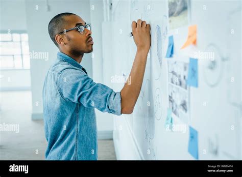 Man writing on whiteboard in office Stock Photo - Alamy