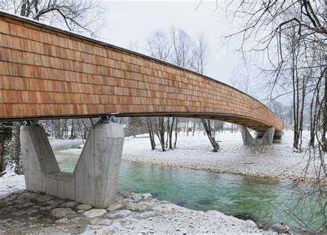 Architects create beautiful arched footbridge out of timber planks and shingles