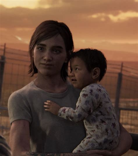 a woman holding a child in her arms near a fence and barbed area at sunset