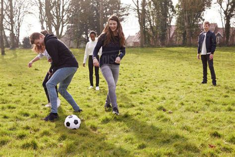 Group of teenagers playing soccer in park together - Stock Photo - Dissolve