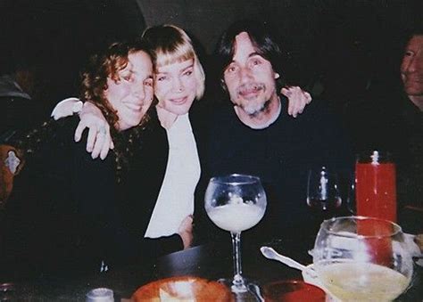 two women and a man sitting at a table with drinks in front of them ...