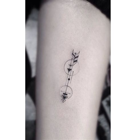 a small black and white photo of a person's arm with an arrow tattoo on it