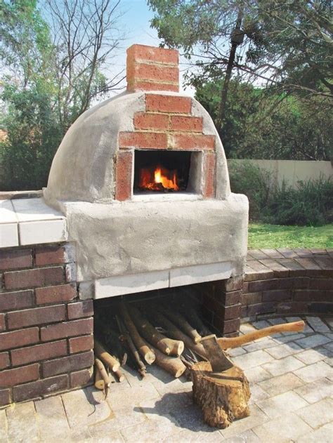 an outdoor pizza oven with logs in front of it