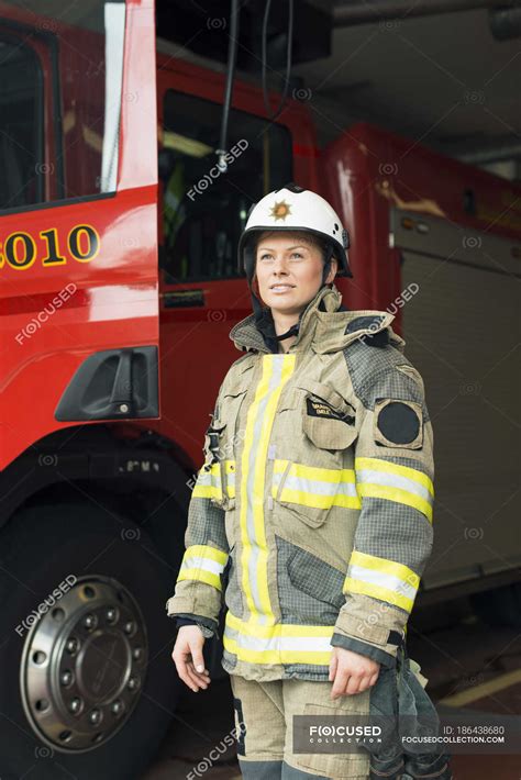 Female firefighter in uniform standing by fire engine — middle age ...