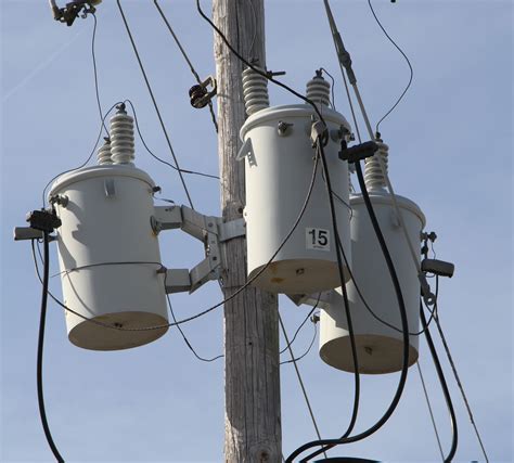 Three White Distribution Transformers on pole with light blue sky - Metglas, Inc.