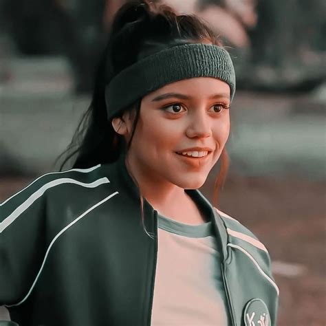 a close up of a person wearing a green jacket and headband with a smile on her face