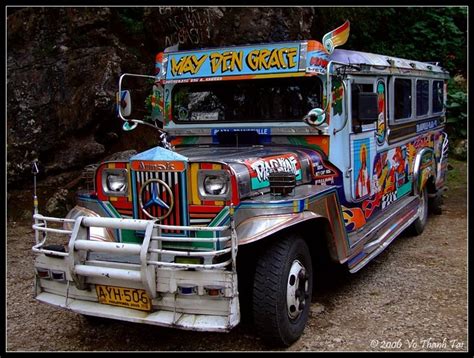 an old school bus painted with colorful paint on it's front and side is parked in the dirt