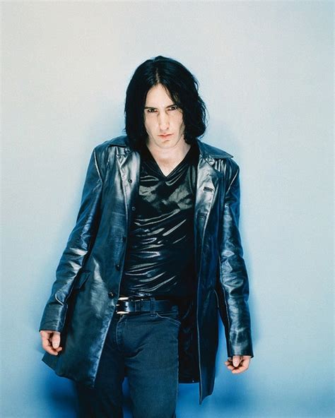 a man with long hair wearing a black leather jacket and jeans, standing ...