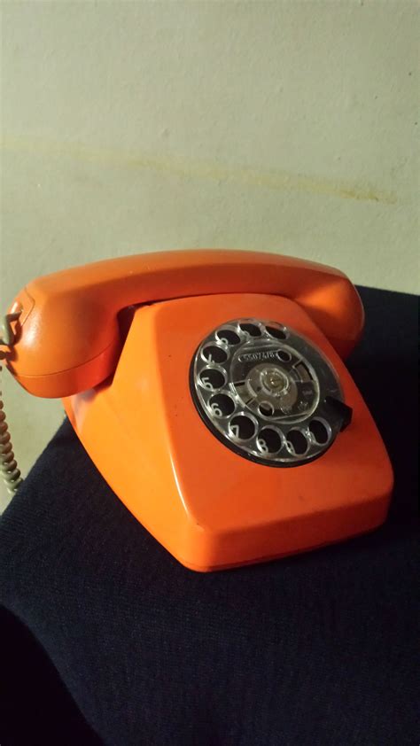 an orange telephone sitting on top of a black table