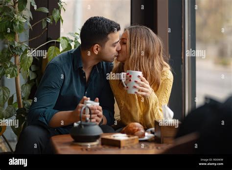 Young attractive couple kissing on date in coffee shop. In love man and woman sitting in a cafe ...