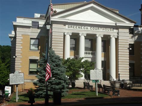 an old courthouse building with columns and flags on the front lawn in front of it