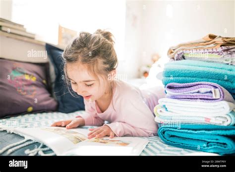 Little girl lying down looking at book Stock Photo - Alamy