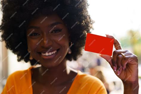 Premium Photo | Portrait of young american woman with afro hairstyle holding red plastic credit card