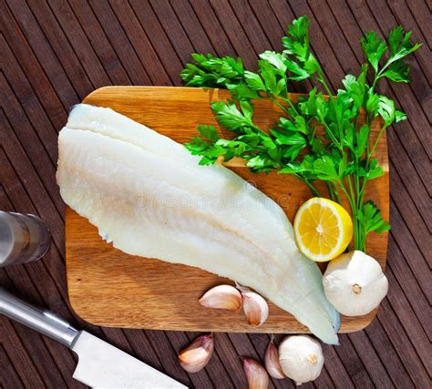 Raw Cod Fillet with Garlic and Lemon on Wooden Surface Stock Photo ...