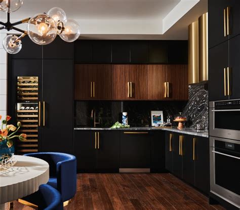 a modern kitchen with black cabinets and gold trim on the doors, wood flooring