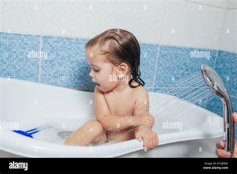 Belle petite fille prendre un bain à la maison. Un mignon bébé est assis dans la salle de bains ...