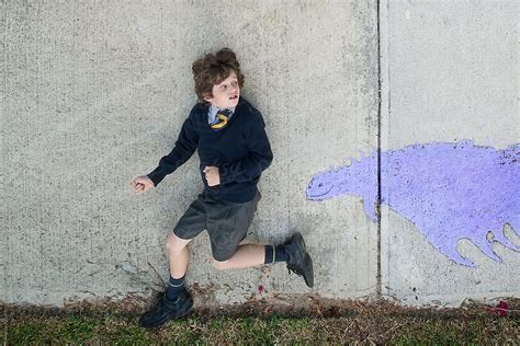 "School Boy Running Away From A Pavement Monster" by Stocksy Contributor "Angela Lumsden" - Stocksy