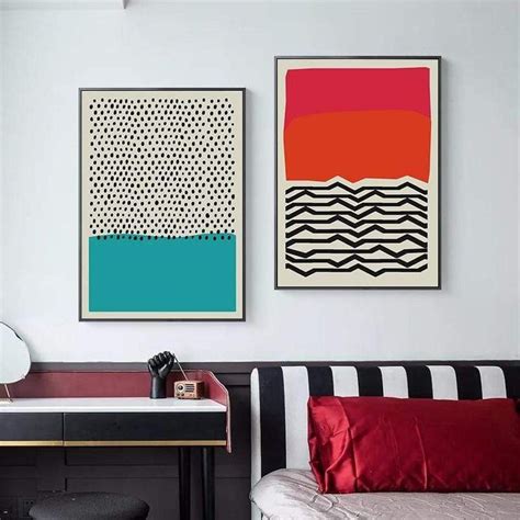 two paintings hang on the wall above a desk in a room with black and ...