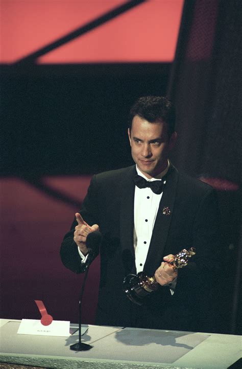 a man in a tuxedo holding an award while standing next to a microphone