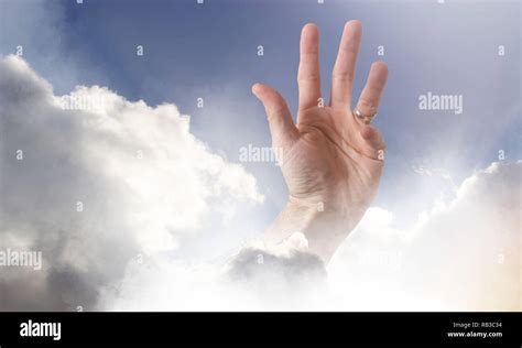 A hand reaching through clouds into a peaceful blue sky representing a concept of recovery or ...