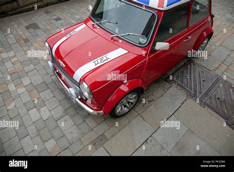 A Red Mini Cooper wth a Union Jack Roof by John Cooper version of the mini parked on a cobbled ...