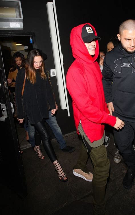 a man in a red hoodie and green pants is walking through a group of people