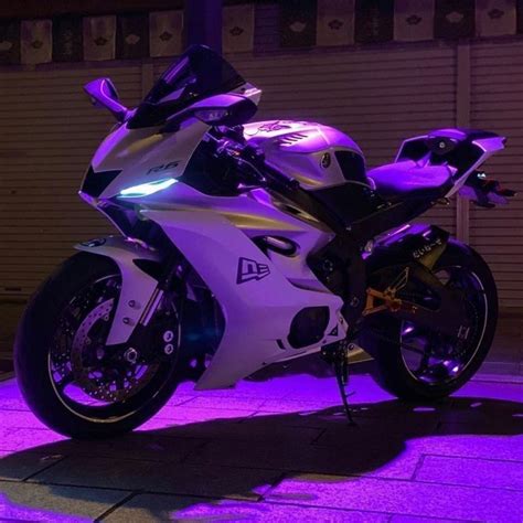 a white and black motorcycle parked in front of a building with purple ...