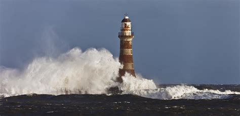 Waves Crashing Against A Lighthouse Photograph by John Short