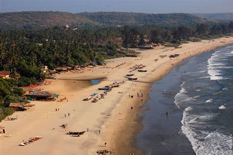 an aerial view of a beach with boats and people on the sand, surrounded by trees