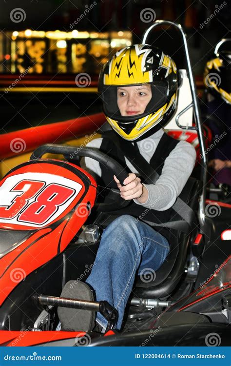 A Young Woman in a Helmet in a Go-kart on the Karting Track Indoors ...