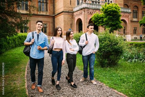 College students walking together outdoors. Group of young people in college campus University ...