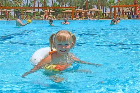 Premium Photo | Smiling baby girl with nice plaits swimming in swimming pool lying on inflatable ...