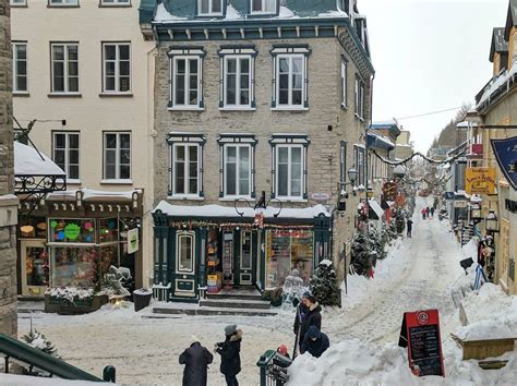 people are walking in the snow on a city street with shops and ...